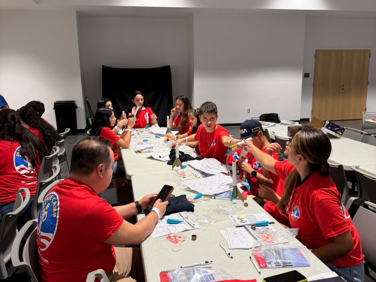 Tripulantes construyendo cohetes alrededor de una mesa de trabajo